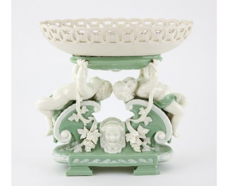 Mintons pale green and white glazed figural centrepiece, two putti holding up an oval pierced basket on scrolling mask decora