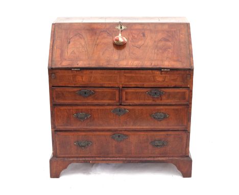 George II walnut bureau with herringbone cross-banding, flap enclosing cupboard flanked by secret compartments, pigeon holes,