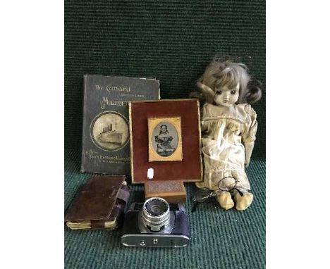 A crate of collectables including porcelain doll, old camera, carved box, Victorian photograph frame, leather wallet of playi