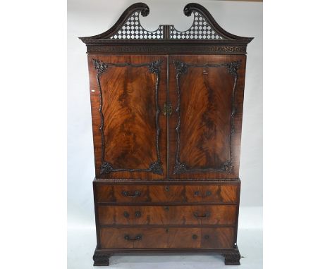 A late 19th / 20th century Chippendale style linen press, the pierced broken swan-neck pediment over pair of moulded panel do