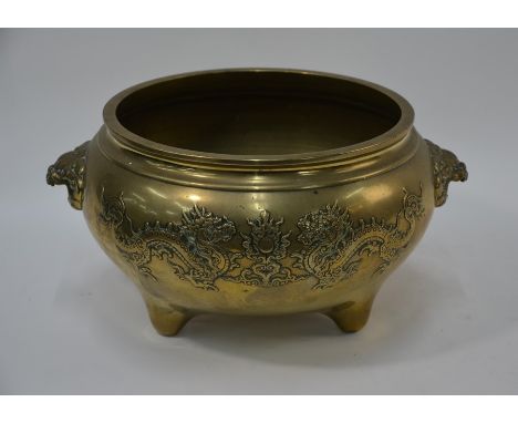A large 19th century Chinese brass tripod censer, each side decorated in relief with two dragons disputing a flaming pearl se