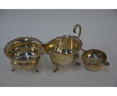 An Edwardian silver cream jug and similar sugar bowl, on hoof feet, Birmingham 1907 to/w a tea strainer on stand, Birmingham 