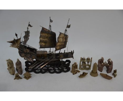 An early 20th century Chinese white metal model of a junk mounted on a naturalistic carved hardwood wave base, the stern with