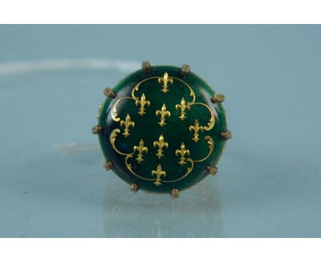 An unusual enamel decorated ring, the centre round green enamelled panel with inlaid fleur de lis pattern in ten claw setting
