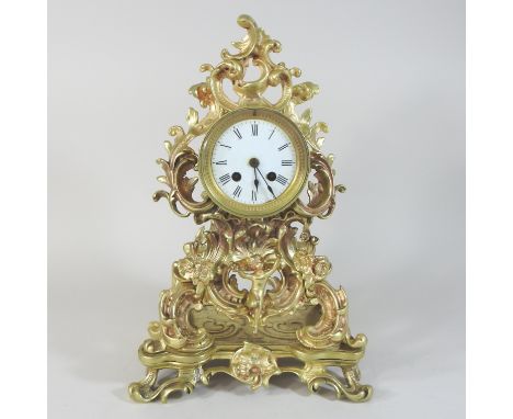 A 19th century brass cased eight day mantel clock, of foliate design, surmounted by a figure of a boy, the white enamel dial 