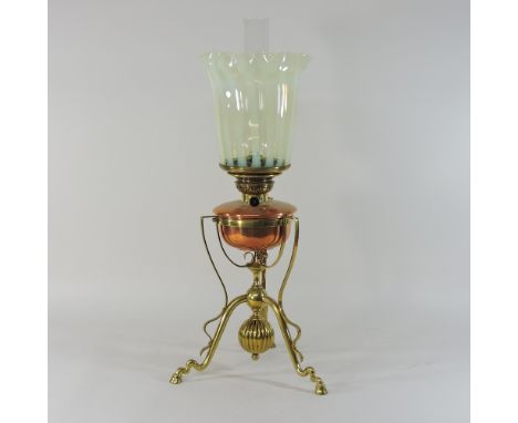 An Arts and Crafts brass and copper oil lamp, on three hoof feet, with a frilled vaseline glass shade, in the manner of W.A.S