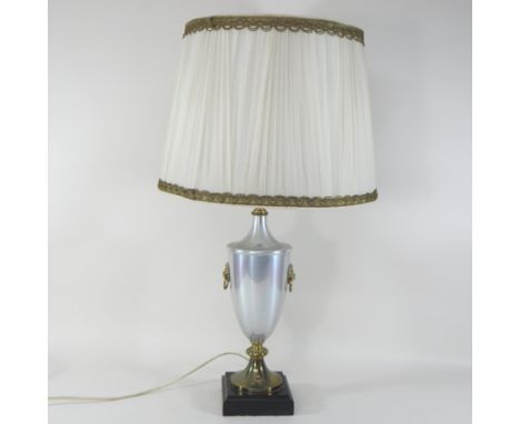 A brass mounted table lamp, of urn shape, on an ebonised plinth base, with a cream shade, 81cm high overall