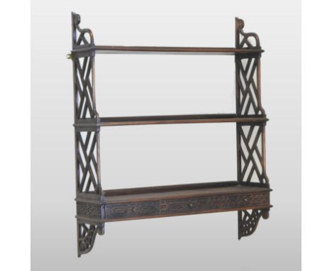 An Edwardian wall shelf, with three graduated tiers, united by openwork supports, with fret carved decoration, 77cm