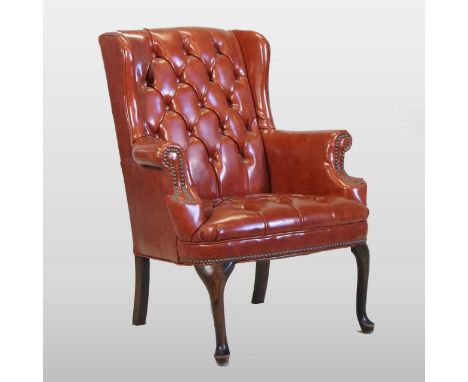 A red upholstered wing armchair, with a button back, on cabriole legs