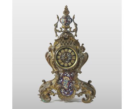 A Rococo style French champleve enamel and gilt metal mantel clock, the scrolled case surmounted by an urn, having a painted 