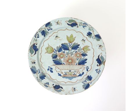 A large delftware plate  18th century, painted in polychrome enamels with tulips and chrysanthemum issuing from a two-handled
