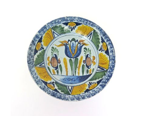A delftware tulip charger  c.1730-40, probably Brislington, brightly decorated in blue, green, yellow and ochre with a large 