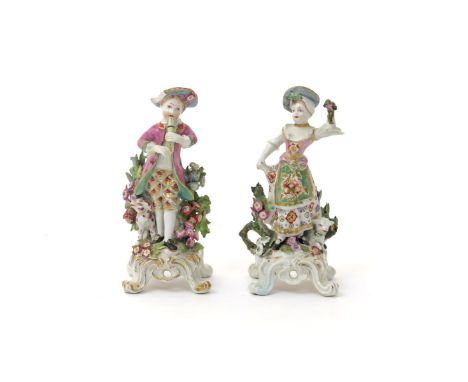 A pair of Bow figures of musicians  c.1770, he playing the flageolet, she dancing beside a lamb, both before flowering bocage