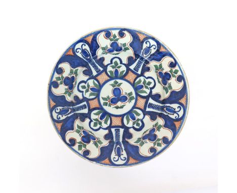 An English delftware large plate  c.1725, perhaps Lambeth, decorated with a formal floral panelled design in blue, red and gr