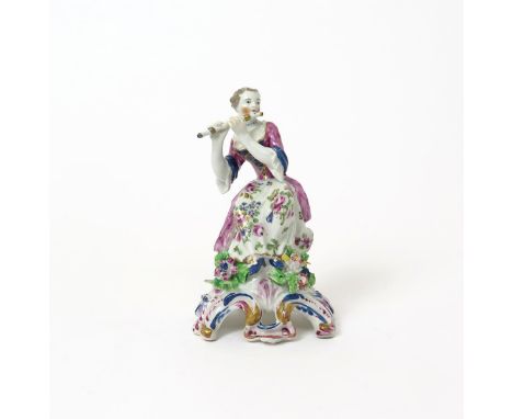 A Bow figure of a female musician  c.1760, seated on a low stump and playing the flute, wearing a flowered skirt, raised on a