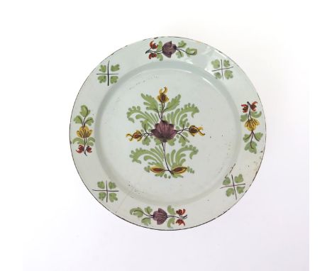 A large English delftware charger  18th century, simply decorated with a floral spray in manganese, yellow, red and green, wi