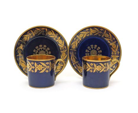 A pair of Sèvres coffee cans and saucers  c.1840, decorated with a continuous formal flowerhead border in gilt on a rich blue