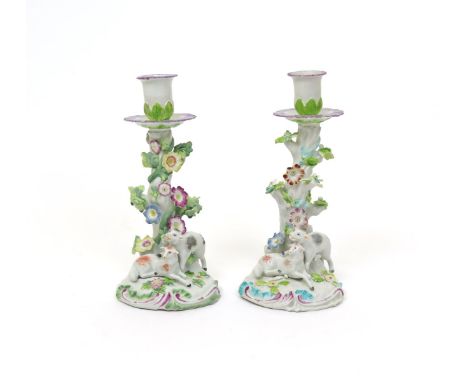 Two Chelsea porcelain candlseticks  c.1758-60, each modelled with two playful lambs at the base of a trunk entwined with flow