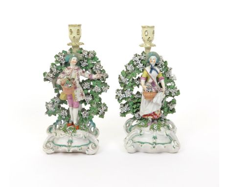 A large pair of Derby candlestick figures  c.1760-65, of a gallant and his companion each standing before flowering bocage wi