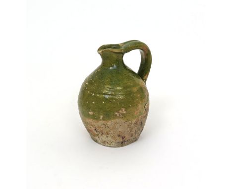 A green-glazed earthenware jug  19th century or earlier, the rounded body decorated to the upper half in a light green glaze,
