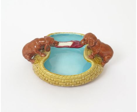 A Villeroy & Bosch Majolica sweetmeat dish  19th century, modelled as two dachshund puppies playing tug of war with a slipper