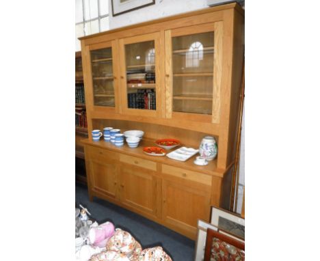 A CONTEMPORARY SOLID LIGHT OAK DRESSER, the upper glazed section above an open top, with three drawers and three cupboard doo