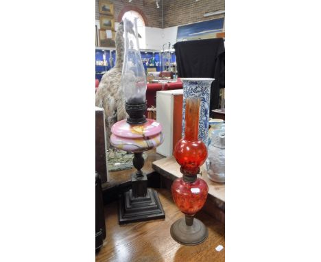 AN EDWARDIAN OIL LAMP with a pink glass reservoir and another similar (2)