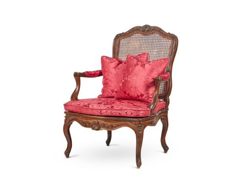 A FRENCH CARVED WALNUT AND BEECH CANED FAUTEUIL IN LOUIS XV STYLE LATE 19TH CENTURY Of large scale, with a foliate carved top