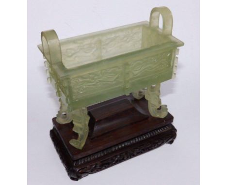 A 20thC Chinese jade of archaic form, the rectangular body with a pair of upturned handles, raised on four tall scroll feet, 