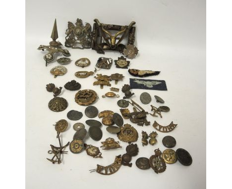 Quantity of military badges, a brass trench art buckle and a helmet finial