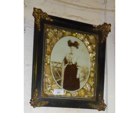 Victorian ornate photo frame with abalone shell border and brass corners flanking a sepia photograph portrait of a woman in a