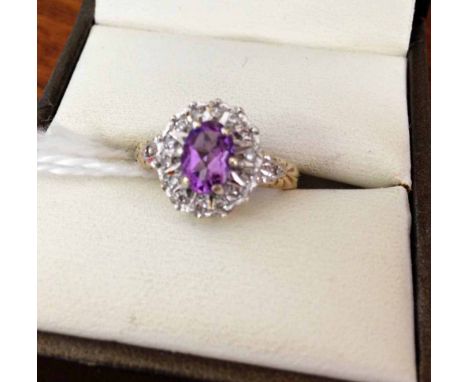 9ct gold ladies dress ring set with central oval amethyst surrounded by small diamonds. Size K.