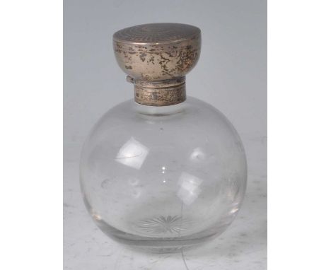 An Art Deco silver and clear glass bodied perfume bottle, the circular engine turned silver hinged cover enclosing glass stop