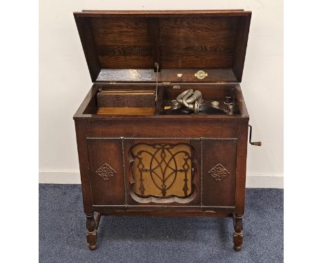 1930s GILBERT GRAMOPHONEin an oak case with a lift up lid above a sliding door opening to reveal a speaker, standing on turne