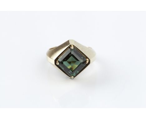 A TSAVORITE GARNET SINGLE STONE RING, the square step-cut garnet with canted corners, claw set to a panelled mount of part-br