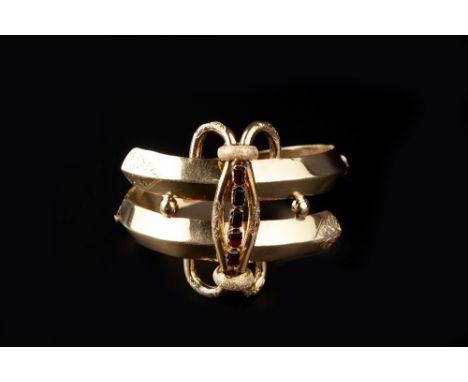 A GEM SET BANGLE, of hinged crossover design, with foliate scroll decoration, centred with a channel of rectangular step-cut 