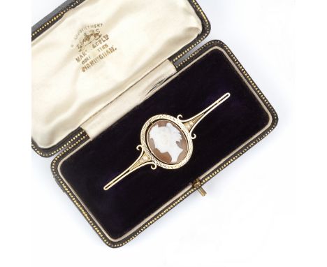A SHELL CAMEO BAR BROOCH, the oval shell cameo carved to depict a classical female portrait in profile, to a tapered and scro