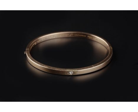 A VICTORIAN DIAMOND SET BANGLE, of hinged oval form, centred with an old-cut diamond in lozenge-shaped setting, the interior 