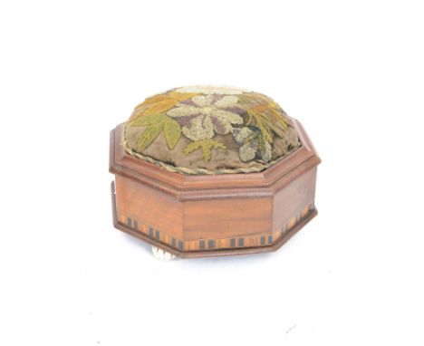 Early 20th century octagonal wooden sewing box, with inlaid sides and domed floral needlework top, upon three ceramic bun fee