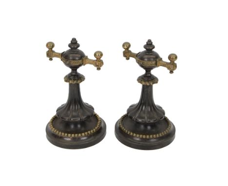 Pair of iron fire dogs, each with circular spreading base with beaded band, leading to a tapering fluted stem supporting a co