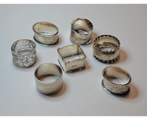 An Edwardian silver napkin ring, having pierced scrolling decoration; together with six other silver napkin rings (7)