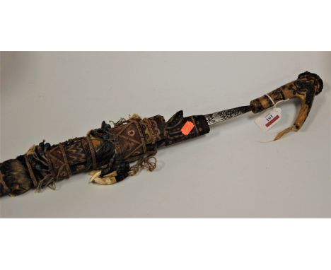 A Borneo head hunter's sword with a carved softwood and polychrome painted and adorned scabbard, the blade with incised decor