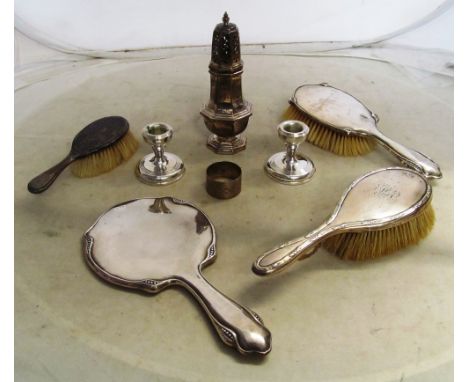 A silver sugar caster, silver backed brushes, mirror, pair of squat candlesticks and a napkin ring