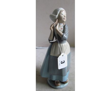 A Lladro figure Dutch girl playing with her plaits