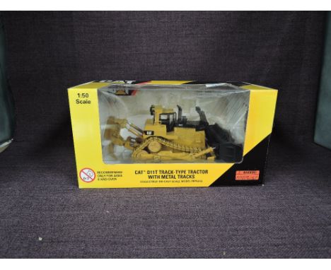 A Norscot 1:50 scale diecast, CAT D11T Track Type Tractor with Metal Tracks in yellow, in plastic packaging and in window dis