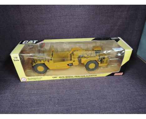 A Norscot 1:50 scale diecast, CAT 657G Wheel Tractor Scraper in yellow, in plastic packaging and in window display box 55175