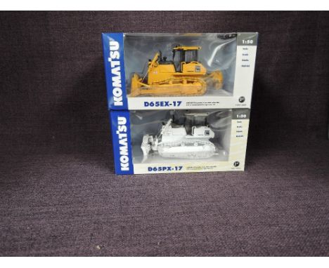 Two First Gear 1:50 scale diecasts, D65EX-17 Crawler Dozer in yellow and D65PX-17 Crawler Dozer in white both in window displ