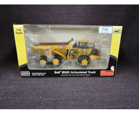 A Norscot 1:50 scale diecast, Bell B50D Articulated Truck in yellow, in plastic packaging and in window display box 57504