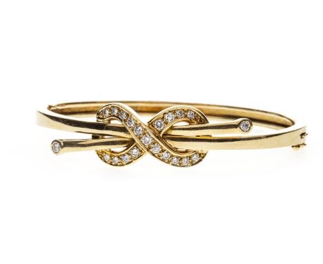 DIAMOND BANGLE, of oval form, with a central diamond set figure of eight through which two torc terminals are set, also set w