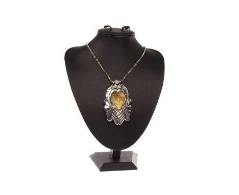 SCOTTISH SILVER AND AMBER PENDANT ON CHAIN BY DOMHMULL DEAN, set with a carved Baltic amber face within an ornate silver moun